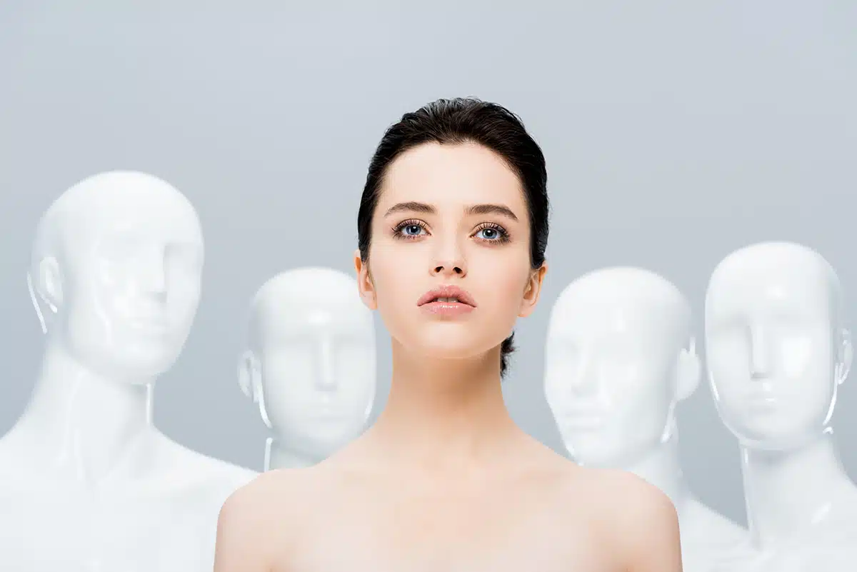 beautiful naked girl posing near mannequins isolated on grey